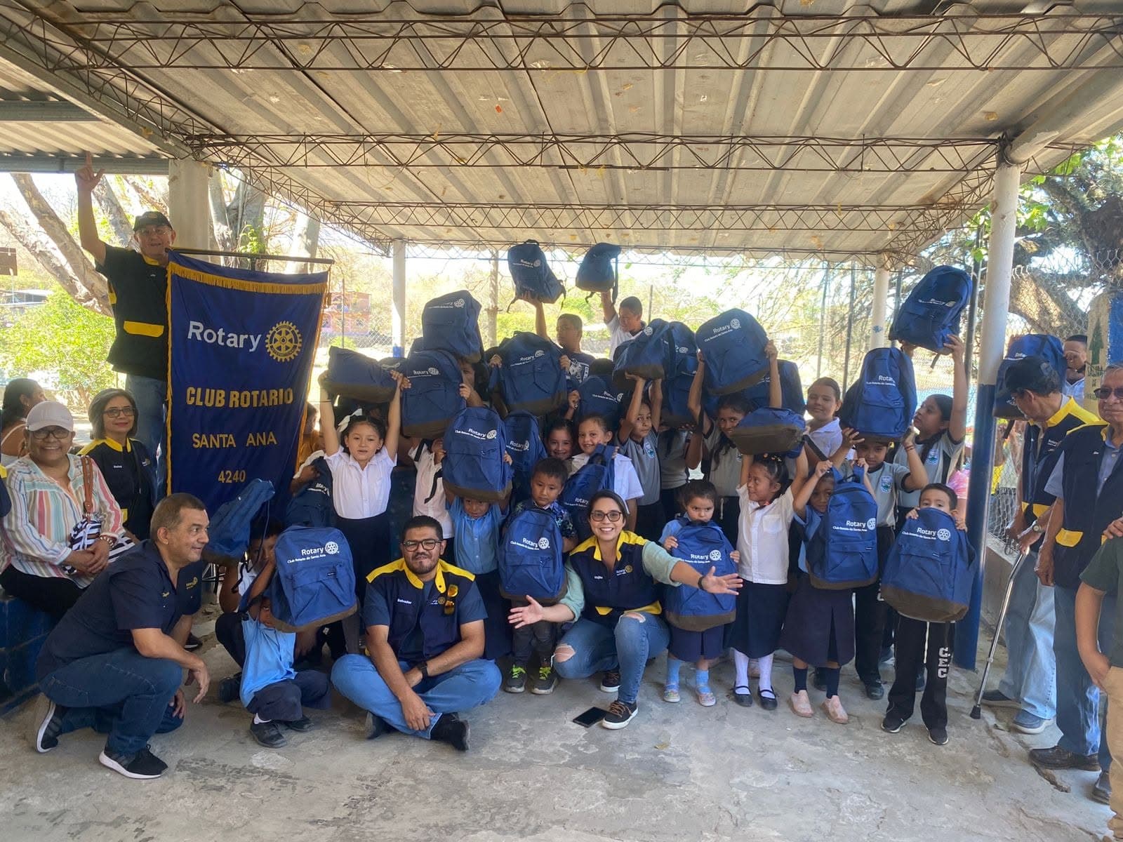 Miembros del Club Rotario de Santa Ana entregando mochilas escolares a niños de la comunidad